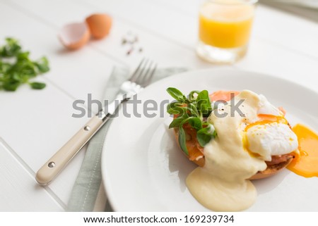 Poached eggs royale with salmon, sauce hollandaise, salad and fresh orange juice. Running egg yolk.