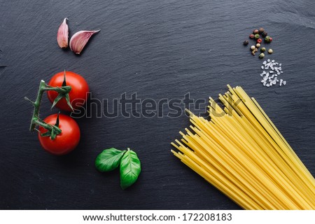Pasta ingredients concept on black slate background viewed from the top