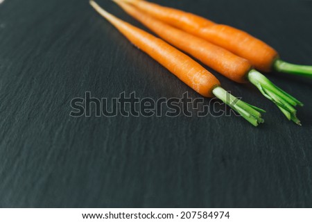 Baby carrots on black slate background