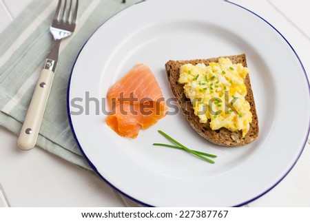 Healthy breakfast with scrambled eggs on toast, smoked salmon, fresh orange juice and green salad