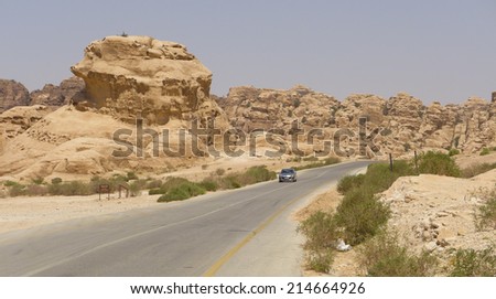 Desert road with singular car approaching. Jordan, between Petra and Dead sea.