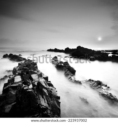Beautiful sunrise landscape seascape over rocky coastline. Black & White minimalist seascape with rocks in black and white