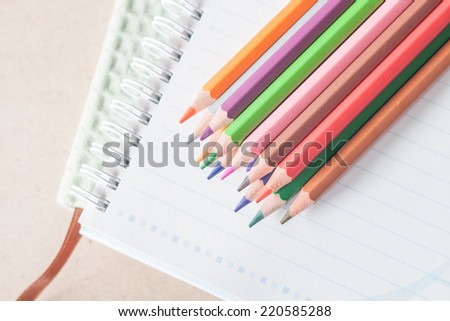 Top view of colorful pencil crayons on spiral notebook and green notebook, stock photo