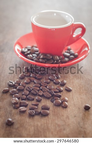 Red coffee cup with coffee beans on wooden table, stock photo