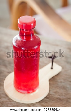 Red syrup in the bottle on wooden plate, stock photo