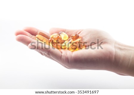 Hand holding fish oil capsules on white background, stock photo