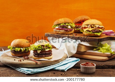 Five gourmet burgers on bright orange background