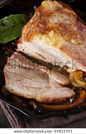Pork shoulder roasted with onion and lemon in a cast-iron baking dish