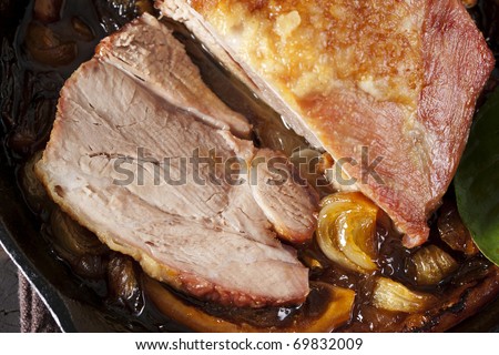 Pork shoulder roasted with onion and lemon in a cast-iron baking dish