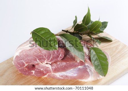 Raw pork shoulder with a bay leaf on a cutting board