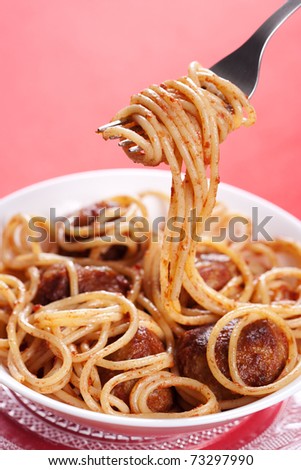 Pasta with meatballs and tomato sauce on red background