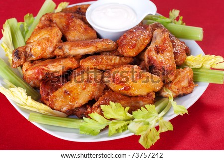 Buffalo chicken wings on plate with blue cheese sauce and celery.