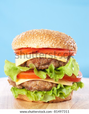 Double cheeseburger with tomatoes and lettuce on blue background