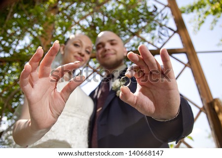bride and groom holding wedding rings, face out of focus