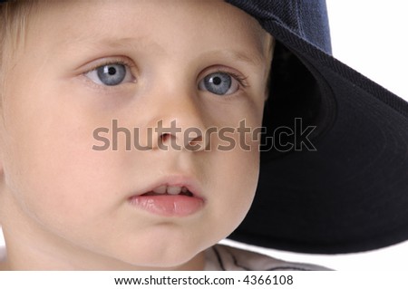 portrait of a young boy with big blue eyes with his black hat on sideways isolated on white