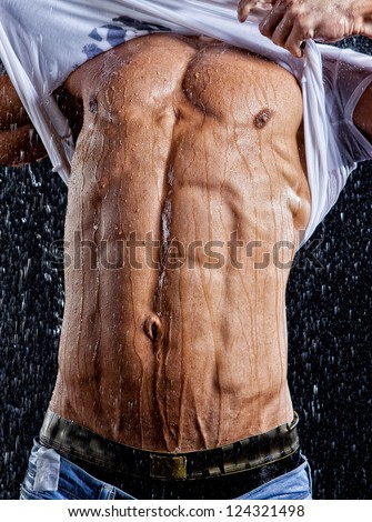 Wet muscle sexy young man torso under the rain in studio