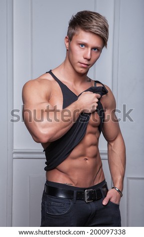 Muscular young sexy athlete posing in black shirt