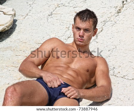 stock photo Muscle wet sexy naked man lying on rock outdoors