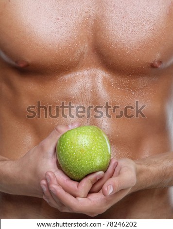 Muscle sexy wet naked young man torso and green apple in hands