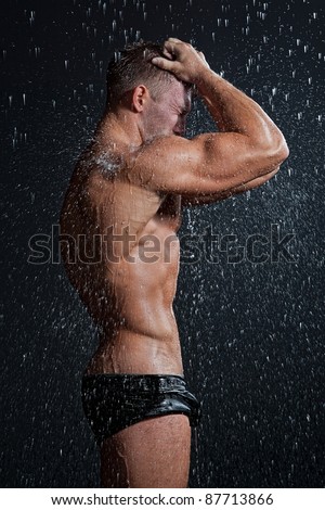 stock photo Muscle wet sexy young naked boy in black trunks posing under