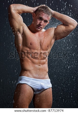stock photo Muscle wet sexy young naked boy in white trunks posing under 