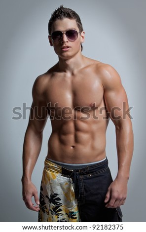 stock photo The muscular young naked smiling sexy boy in the beach shorts 