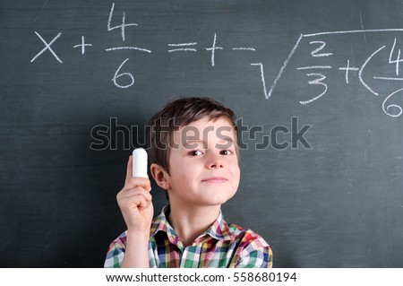 Young math genius in front of blackboard with mathematical problem and chalk in his hand