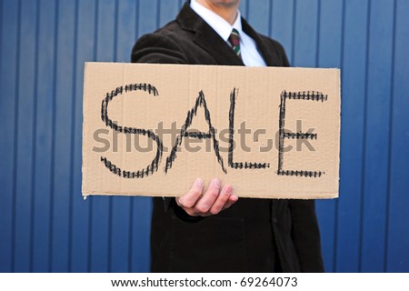 Man is holding a cardboard-sign advertising a sale