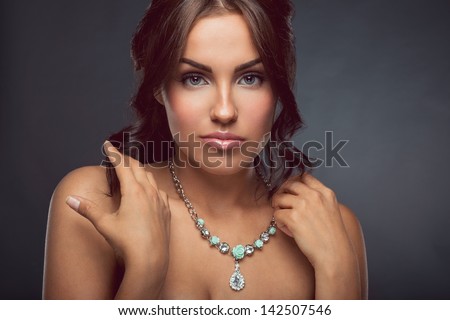 Beautiful young lady with curly hair posing in studio with silver necklace