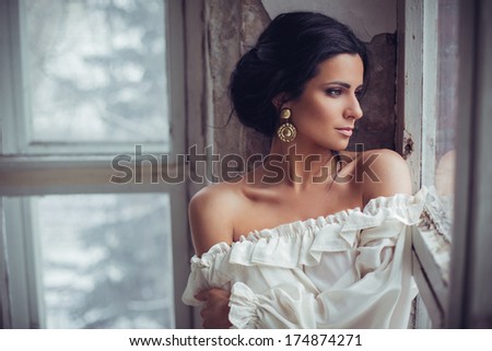 Beautiful brunette in white dress posing indoors