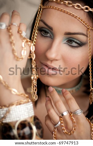 Portrait of a young woman looking at golden chains on her hand