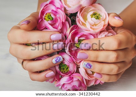 Close up light pink nail art with printed flowers on light wood background
