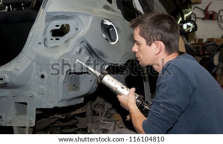 Worker repairing a car body.