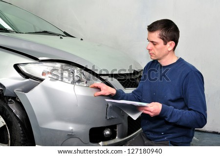 Insurance expert examining car damage.