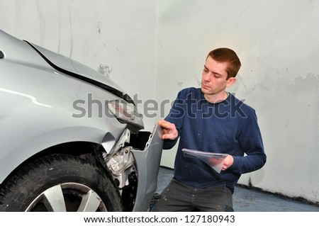 Insurance expert examining car damage.