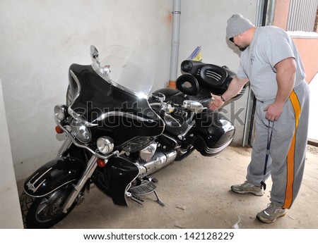KIEV, UKRAINE - 20 MARCH 2013: The World\'s Strongest Man Vasyl Virastuk checks own motorcycle in garage on March 20, 2013 in Kiev, Ukraine.