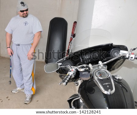 KIEV, UKRAINE - 20 MARCH 2013: The World\'s Strongest Man Vasyl Virastuk checks own motorcycle in garage on March 20, 2013 in Kiev, Ukraine.