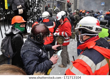 KIEV, UKRAINE - 22 JANUARY 2014: Unknown volunteers from Red Cross work during street fight in government district on January 22, 2014 in Kiev, Ukraine.