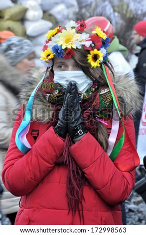 KIEV, UKRAINE - 24 JANUARY 2014: Unknown girl prays for peace during street fight with police in government district on January 24, 2014 in Kiev, Ukraine.