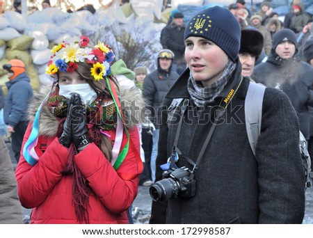 KIEV, UKRAINE - 24 JANUARY 2014: Unknown girl and boy pray for peace during street fight with police in government district on January 24, 2014 in Kiev, Ukraine.
