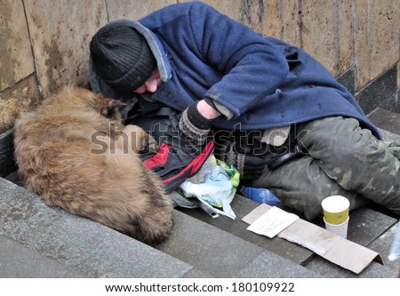 KIEV, UKRAINE - 24 FEBRUARY 2013: Unknown pauper with dog requests for money on a city street on February 24, 2013 in Kiev, Ukraine.