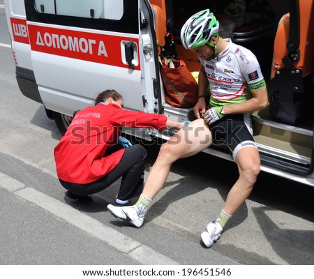 KIEV, UKRAINE - 1 JUNE 2014: Unknown doctor gives a medical help to unknown cyclist after road accident on June 1, 2014 in Kiev, Ukraine.