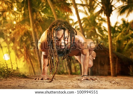Yoga handstand pose by fit man with dreadlocks on the road near the fishermen hut in Varkala, Kerala, India
