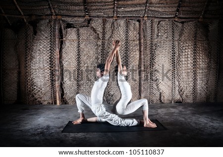 Couple yoga of woman and man doing ashwa sanchalanasana lunge pose in white cloth in yoga hall, Varkala, Kerala, India