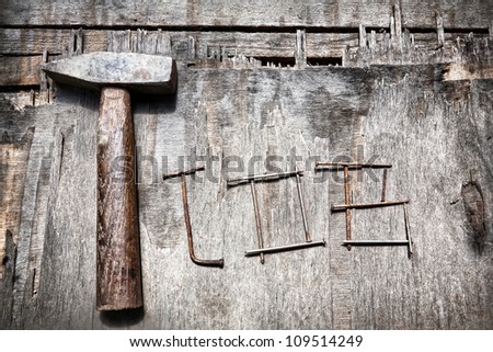 Job word from nails and old hammer on the textured wooded background