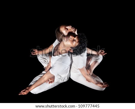 Couple Yoga meditation of man and woman in white cloth doing padmasana lotus pose with closed eyes isolated on black background