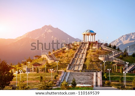View to the monument with stairs and mountains at sunrise sky background in dendra park of first president Nursultan Nazarbayev in Almaty, Kazakhstan