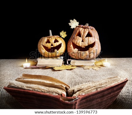 Halloween pumpkins reading old book at black background