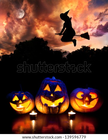 Halloween Glowing Pumpkins On The Table And Witch Silhouette Flying At Dramatic Night Sky With Moon