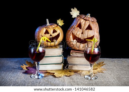 Funny Halloween pumpkins drinking wine on the heap of books at black background